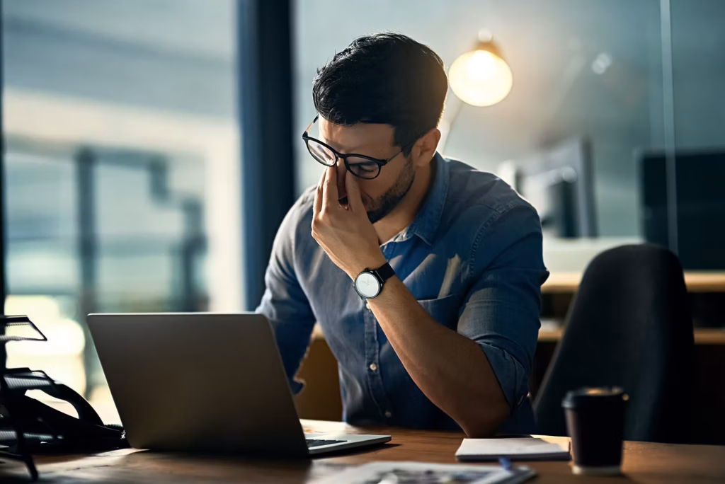 An employee working at a laptop stressed out.
